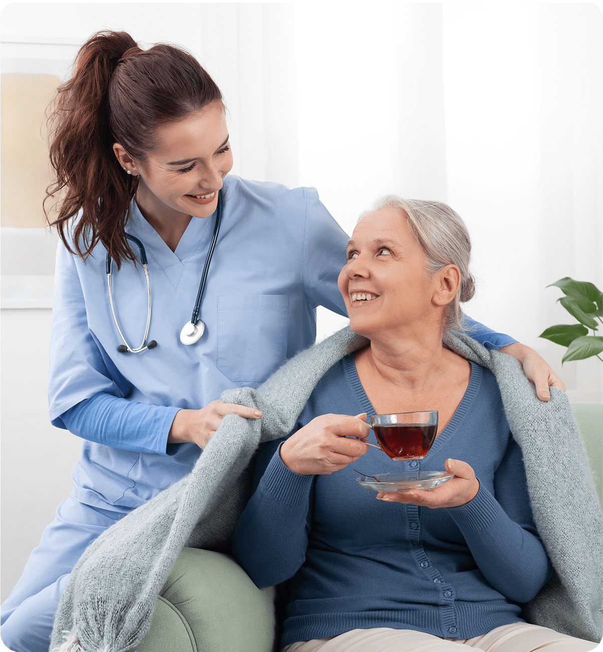 Nurse assisting elderly woman with tea.