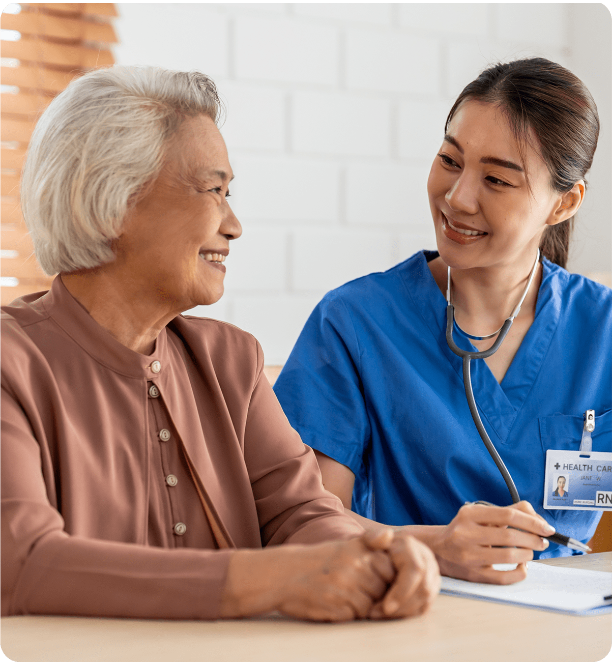 A healthcare worker engaging warmly with an elderly woman.