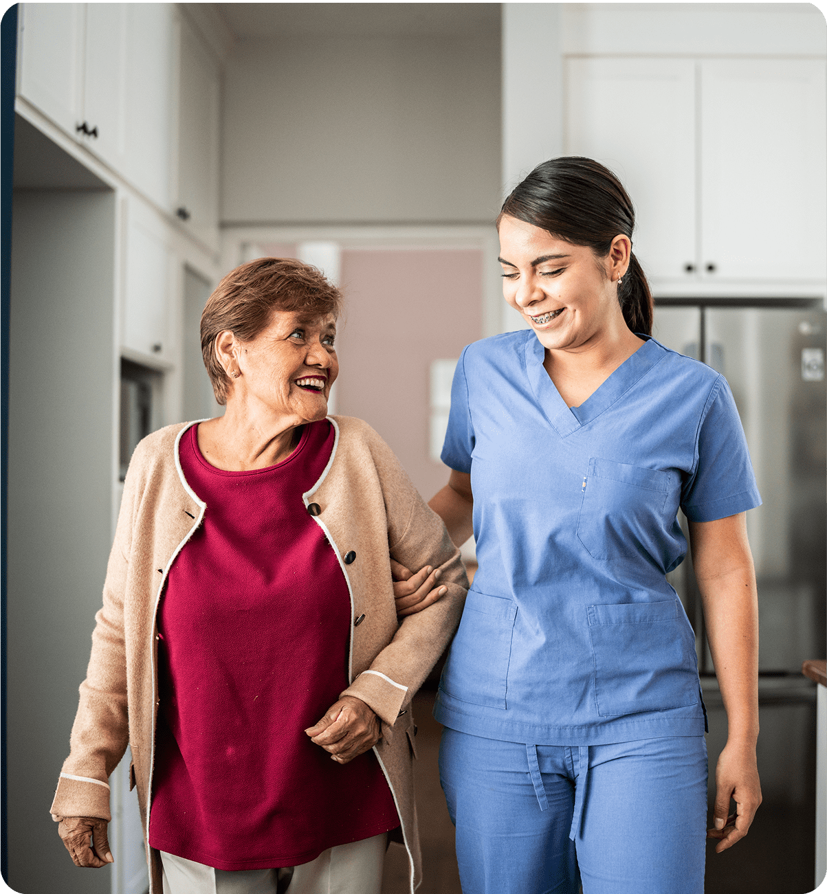 A nurse assists an elderly woman walking indoors.