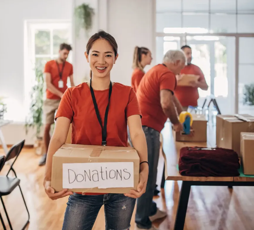 Smiling volunteer holding a donations box at a charity event.