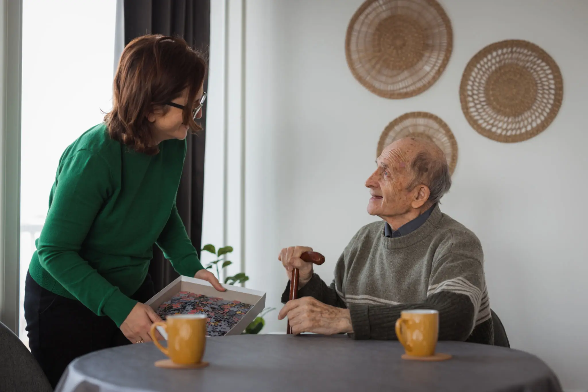 An elderly man and a woman having tea and conversation at a table.