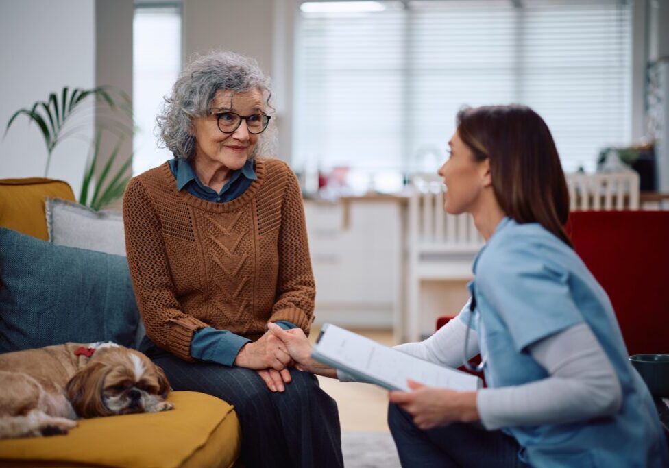 Elderly woman with nurse and dog talking.